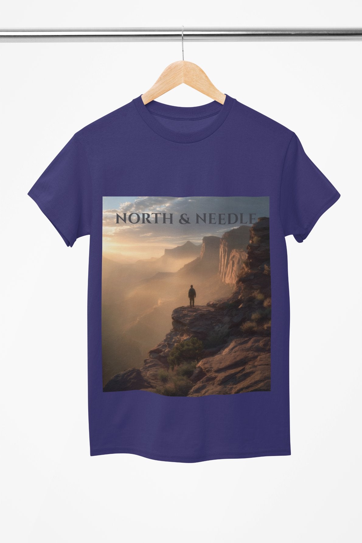 Blue t-shirt with a scenic design and 'North & Needle' text on a hanger.
