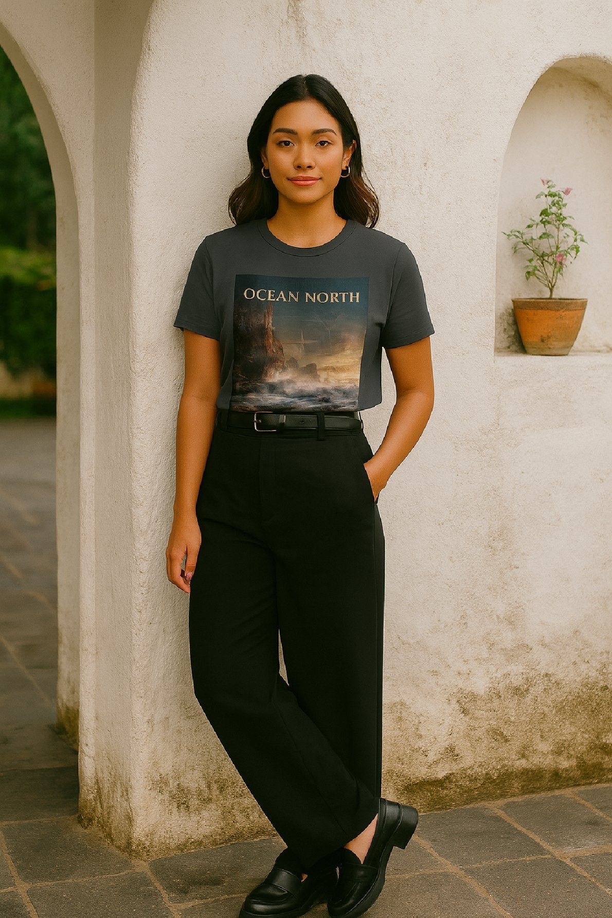 Woman wearing a t-shirt with 'Ocean North' design against a white wall.