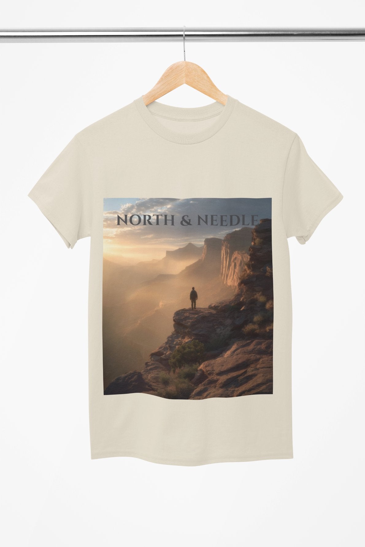 Beige t-shirt with a scenic print featuring 'North & Needle' on a white background