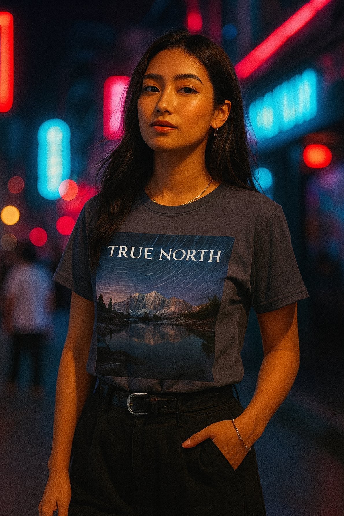 Person wearing a t-shirt with 'True North' graphic design in a neon-lit urban setting